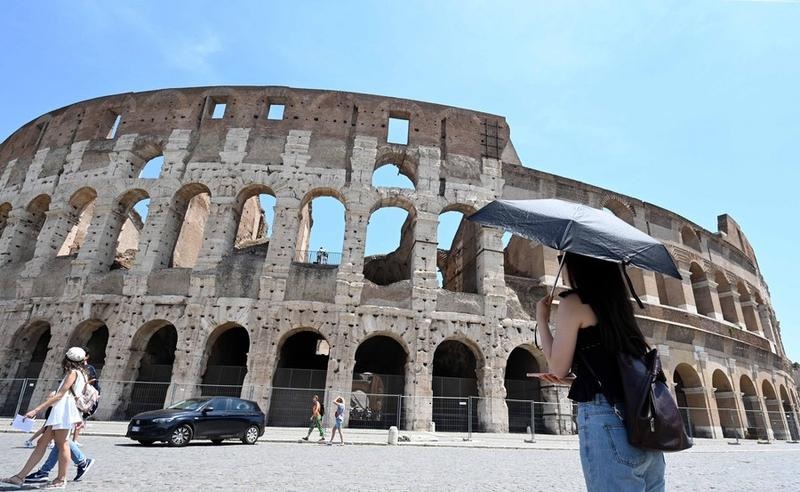 Seorang wanita berlindung dari sinar matahari menggunakan payung di tengah cuaca panas di Colosseum di Roma, Italia, pada 17 Juni 2022. (Xinhua/Alberto Lingria)