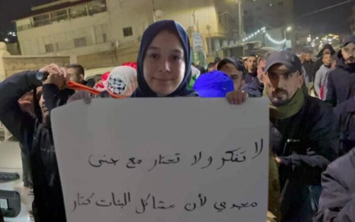 Almarhum Jana Zakarneh membawa poster bertuliskan: "Jangan berpikir dan jangan bingung dengan Jana Majdi karena masalah perempuan itu banyak." Foto: WAFA.