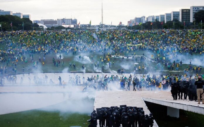 Pendukung mantan Presiden Brasil Jair Bolsonaro berdemonstrasi menentang Presiden Luiz Inacio Lula da Silva saat pasukan keamanan beroperasi, di luar Kongres Nasional Brasil di Brasilia, Brasil, 8 Januari 2023. Foto: Reuters/Adriano Machado.