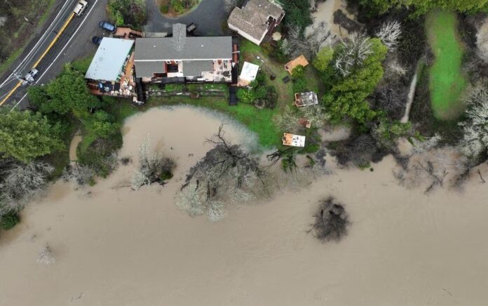 Air banjir dari Sungai Rusia mendekati rumah setelah rangkaian badai musim dingin, di Guerneville, California, AS 15 Januari 2023. Foto: Reuters/Fred Greaves.