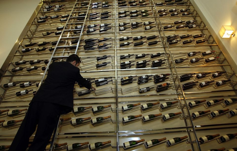 Seorang pelayan mengatur botol anggur di rak anggur raksasa di sebuah bar di Dubai 9 Maret 2011. Foto: REUTERS/Abdullah Muhsen