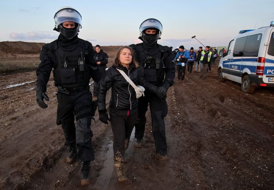 Petugas polisi menahan aktivis iklim Greta Thunberg pada hari protes terhadap perluasan tambang lignit terbuka Garzweiler dari utilitas RWE Jerman ke Luetzerath, di Jerman, 17 Januari 2023 yang menyoroti ketegangan atas kebijakan iklim Jerman selama krisis energi . Foto: Reuters/Wolfgang Rattay.