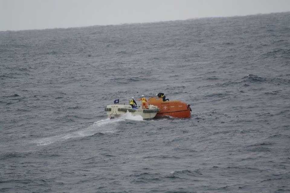 Awak Penjaga Pantai Jepang memeriksa sekoci penyelamat yang hanyut di laut dekat lokasi kapal kargo yang tenggelam di barat daya Jepang dalam gambar selebaran yang dirilis pada 25 Januari 2023. Foto: Penjaga Pantai Jepang/Selebaran via Reuters.