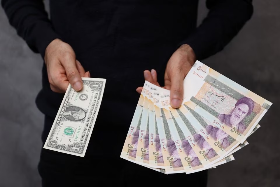 Dealer mata uang berpose untuk foto dengan uang kertas satu dolar AS dan jumlah yang diberikan saat mengubahnya menjadi real Iran di sebuah toko pertukaran di Teheran, Iran 25 Desember 2022. Foto: Majid Asgaripour/WANA/Reuters.