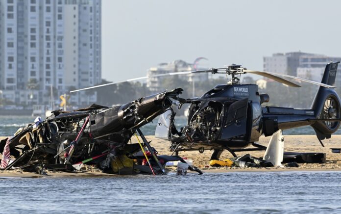 Dua helikopter yang diuangkan duduk di atas pasir di lokasi tabrakan dekat Seaworld, di Gold Coast, Australia, Senin, 2 Januari 2023. Foto: AP.