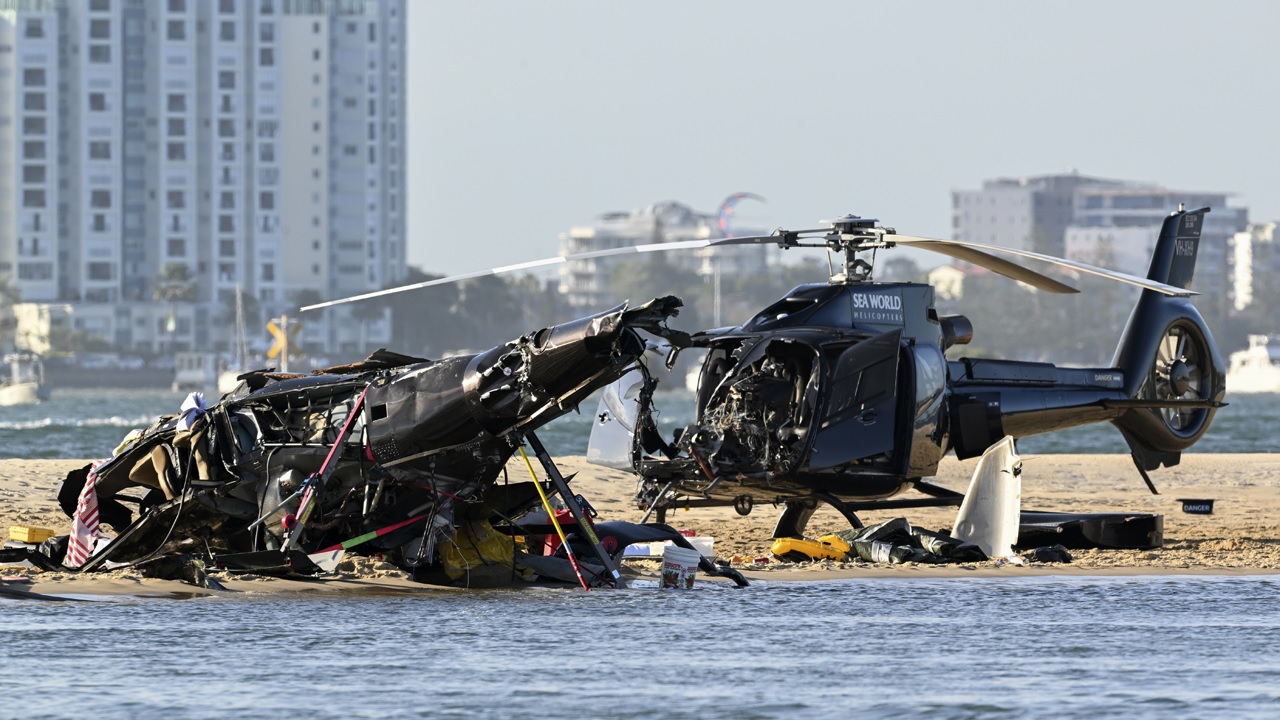 Dua helikopter yang diuangkan duduk di atas pasir di lokasi tabrakan dekat Seaworld, di Gold Coast, Australia, Senin, 2 Januari 2023. Foto: AP.