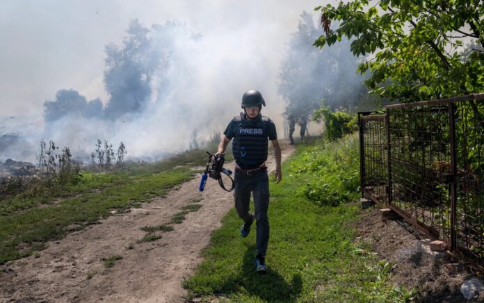 Seorang jurnalis AFP berlari saat asap mengepul setelah pengeboman di Bakhmut, di Ukraina timur, pada 31 Juli 2022. (AFP/Bulent Kilic)