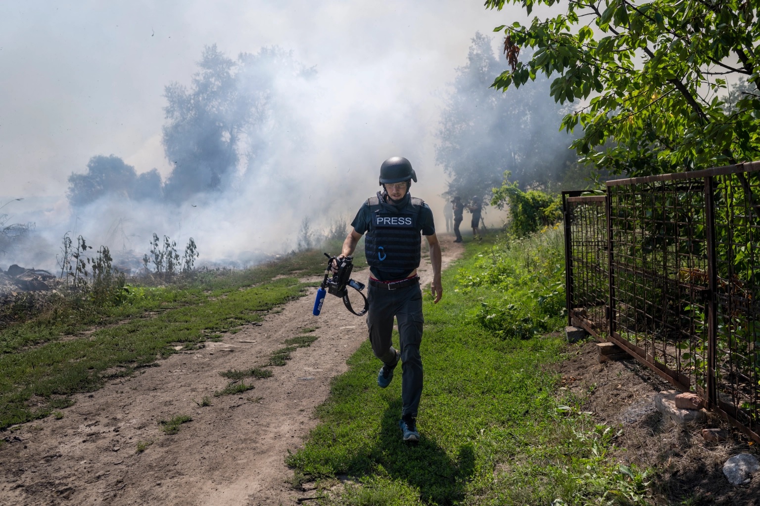Seorang jurnalis AFP berlari saat asap mengepul setelah pengeboman di Bakhmut, di Ukraina timur, pada 31 Juli 2022. (AFP/Bulent Kilic)