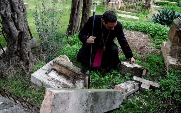 Uskup Agung Hosam Naoum memeriksa batu nisan yang dirusak di Pemakaman Gunung Zion Protestan di Yerusalem 4 Januari 2023. Foto: Reuters/Ammar Awad.
