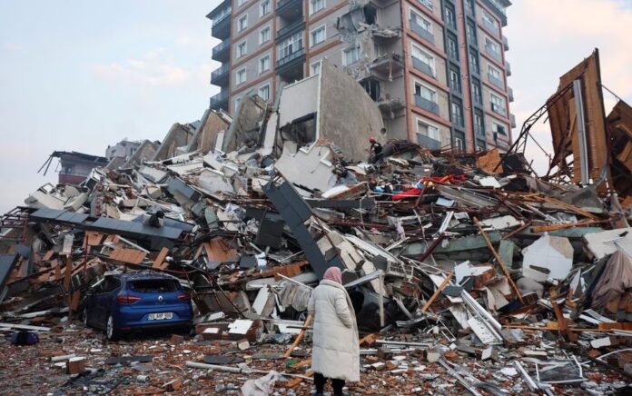 Seorang wanita melihat saat tim penyelamat mencari korban selamat di bawah reruntuhan setelah gempa bumi di Hatay, Turki, 7 Februari 2023. Foto: Reuters/Umit Bektas.