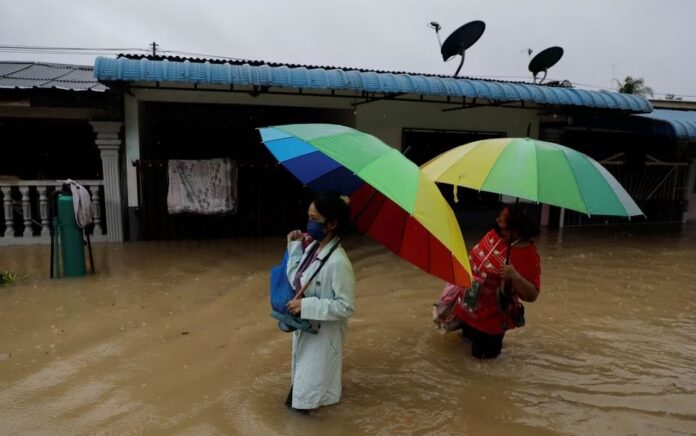 Orang-orang menyeberangi area pemukiman yang terendam banjir di Yong Peng, Johor, Malaysia 4 Maret 2023. Foto: Reuters/Hasnoor Hussain.