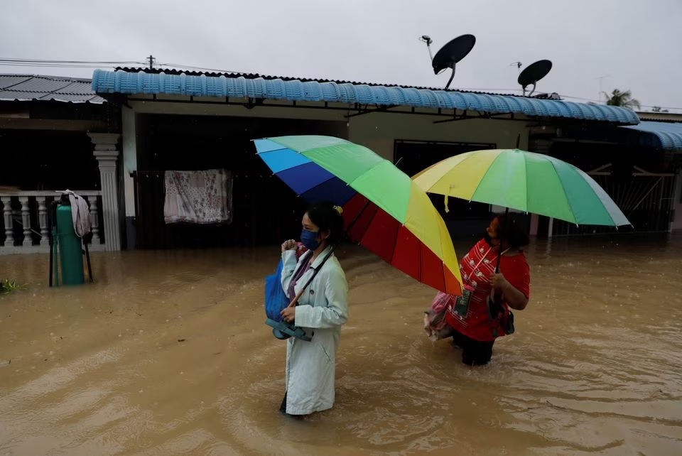 Orang-orang menyeberangi area pemukiman yang terendam banjir di Yong Peng, Johor, Malaysia 4 Maret 2023. Foto: Reuters/Hasnoor Hussain.