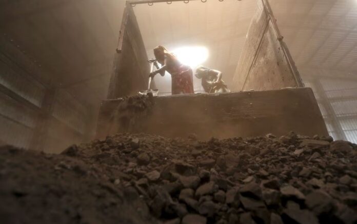 Para pekerja menurunkan batu bara dari truk pasokan di halaman pinggiran kota Ahmedabad, India barat, 15 April 2015. Foto: Reuters/Amit Dave/Files.