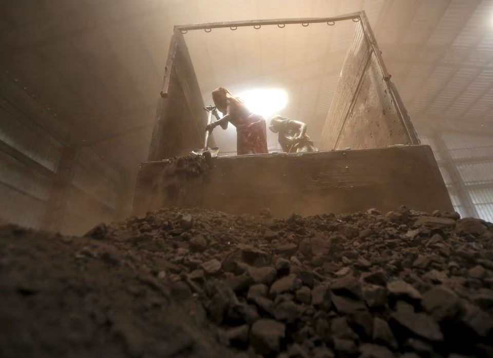 Para pekerja menurunkan batu bara dari truk pasokan di halaman pinggiran kota Ahmedabad, India barat, 15 April 2015. Foto: Reuters/Amit Dave/Files.
