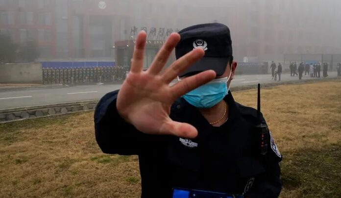 Seorang penjaga keamanan memindahkan wartawan dari Institut Virologi Wuhan. Foto: Foto AP/Ng Han Guan/File.