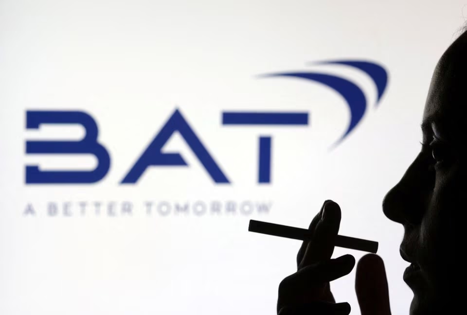 Seorang perempuan berpose dengan sebatang rokok di depan logo BAT (British American Tobacco) dalam ilustrasi yang diambil 26 Juli 2022. Foto: Reuters/Dado Ruvic.