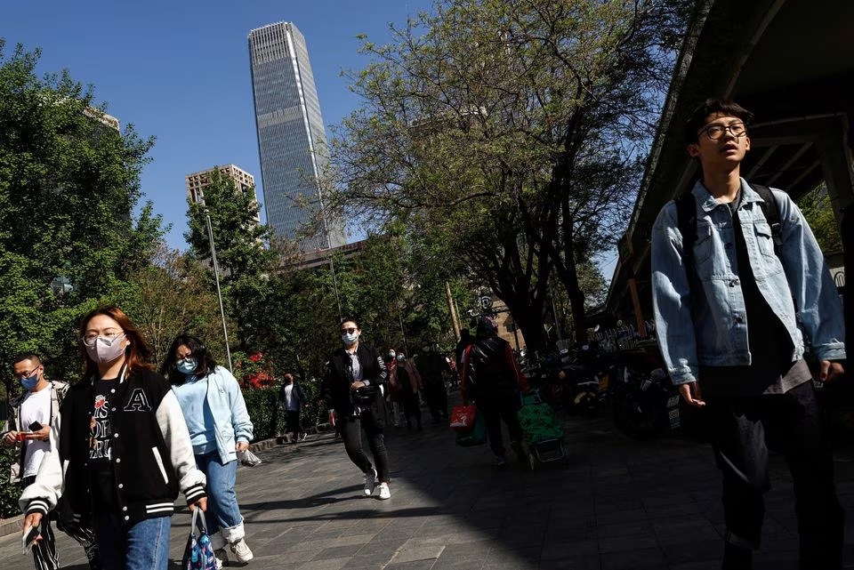 Orang-orang berjalan di jalan di Central Business District (CBD) Beijing pada jam sibuk pagi hari, di Beijing, China 18 April 2023. Foto: Reuters/Tingshu Wang.