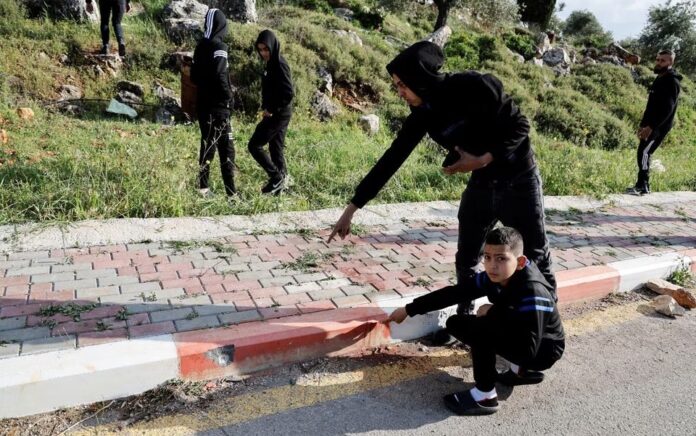 Warga Palestina menunjukkan lubang peluru di lokasi insiden keamanan dekat Nablus di Tepi Barat yang diduduki Israel 11 April 2023. Foto: Reuters/Raneen Sawafta.