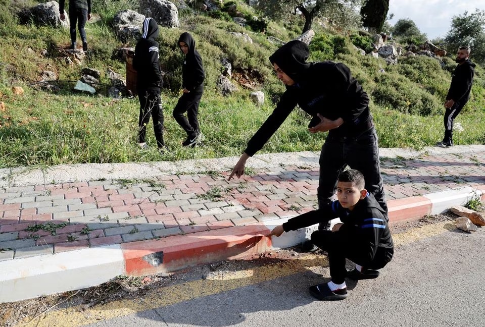 Warga Palestina menunjukkan lubang peluru di lokasi insiden keamanan dekat Nablus di Tepi Barat yang diduduki Israel 11 April 2023. Foto: Reuters/Raneen Sawafta.