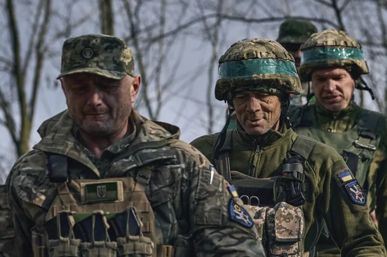 Tentara Ukraina dari brigade ke-28 berjalan bersama di posisi mereka di garis depan dekat Bakhmut, Donetsk. Foto: Foto Libkos/AP.