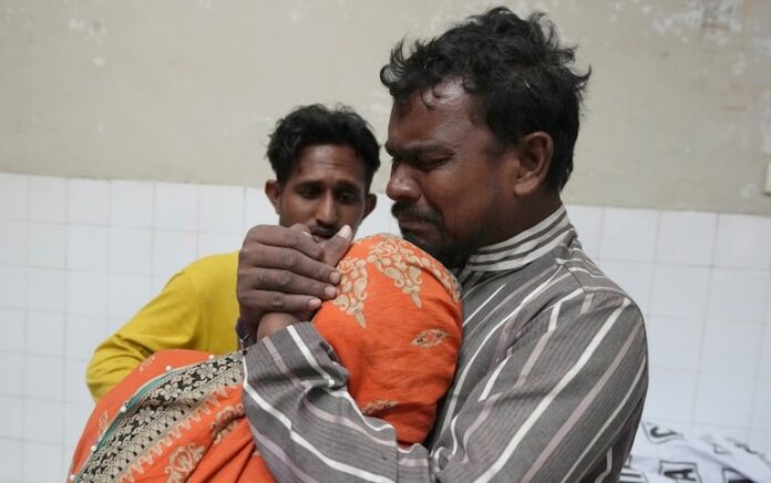 Sebuah keluarga berduka di samping jenazah anggota keluarga mereka, yang meninggal karena terinjak-injak di sebuah pusat distribusi makanan Ramadan. Foto: Foto AP/Fareed Khan.