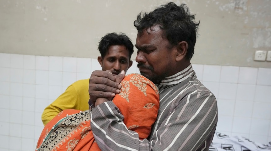Sebuah keluarga berduka di samping jenazah anggota keluarga mereka, yang meninggal karena terinjak-injak di sebuah pusat distribusi makanan Ramadan. Foto: Foto AP/Fareed Khan.