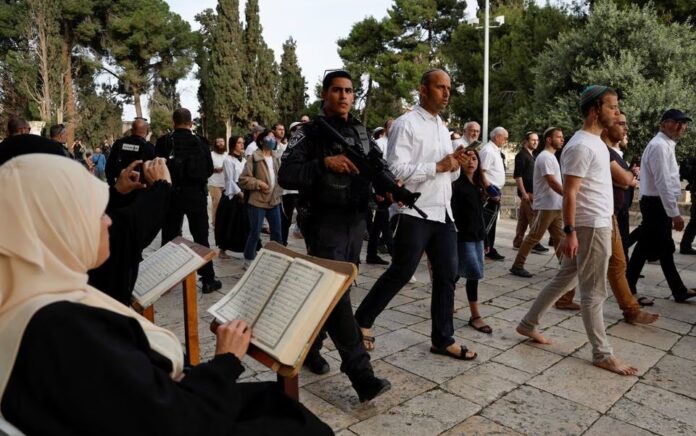 Pengunjung Yahudi berjalan melewati orang-orang yang membaca Alquran, di kompleks Masjid Al-Aqsa, yang dikenal umat Islam sebagai Tempat Suci Mulia dan bagi orang Yahudi sebagai Temple Mount, sementara ketegangan muncul saat bentrokan di Kota Tua Yerusalem, 9 April 2023. Foto: Reuters /Ammar Awad.