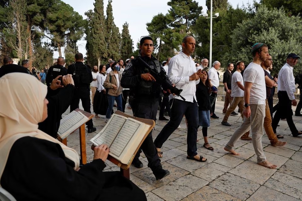 Pengunjung Yahudi berjalan melewati orang-orang yang membaca Alquran, di kompleks Masjid Al-Aqsa, yang dikenal umat Islam sebagai Tempat Suci Mulia dan bagi orang Yahudi sebagai Temple Mount, sementara ketegangan muncul saat bentrokan di Kota Tua Yerusalem, 9 April 2023. Foto: Reuters /Ammar Awad.
