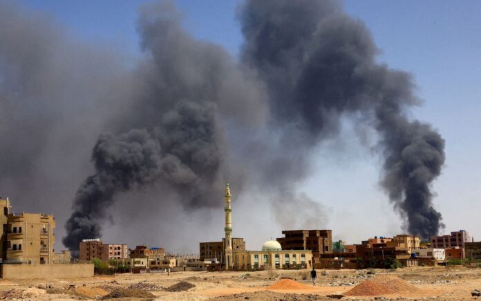 Seorang pria berjalan sementara asap mengepul di atas bangunan setelah pengeboman udara, selama bentrokan antara Pasukan Dukungan Cepat paramiliter dan tentara di Khartoum Utara, Sudan, 1 Mei 2023. Foto: Reuters/Mohamed Nureldin Abdallah.