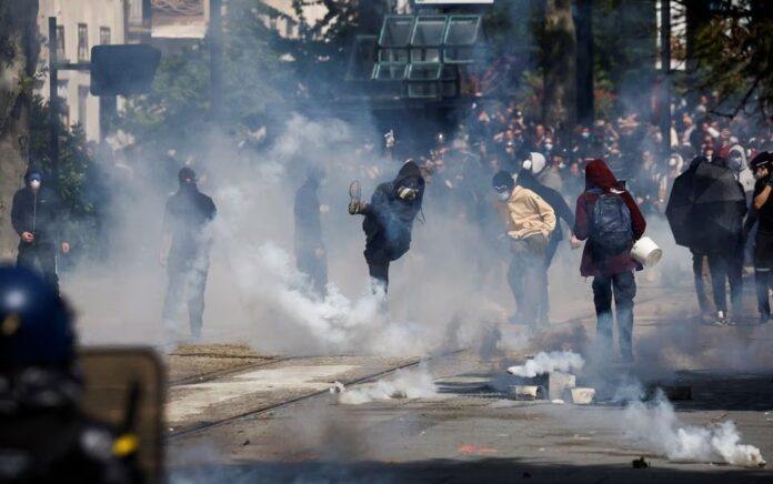 Demonstran melemparkan gas air mata saat mereka bentrok dengan polisi selama pawai buruh Hari Buruh tradisional, hari mobilisasi menentang undang-undang reformasi pensiun Prancis dan untuk keadilan sosial, di Nantes, Prancis 1 Mei 2023. Foto: Reuters/Stephane Mahe.