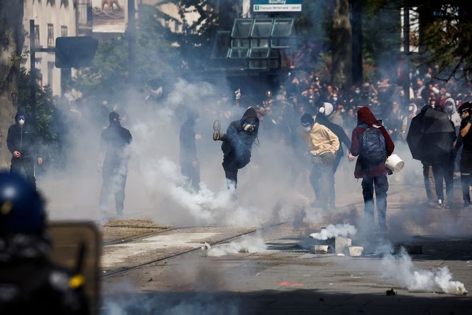 Demonstran melemparkan gas air mata saat mereka bentrok dengan polisi selama pawai buruh Hari Buruh tradisional, hari mobilisasi menentang undang-undang reformasi pensiun Prancis dan untuk keadilan sosial, di Nantes, Prancis 1 Mei 2023. Foto: Reuters/Stephane Mahe.