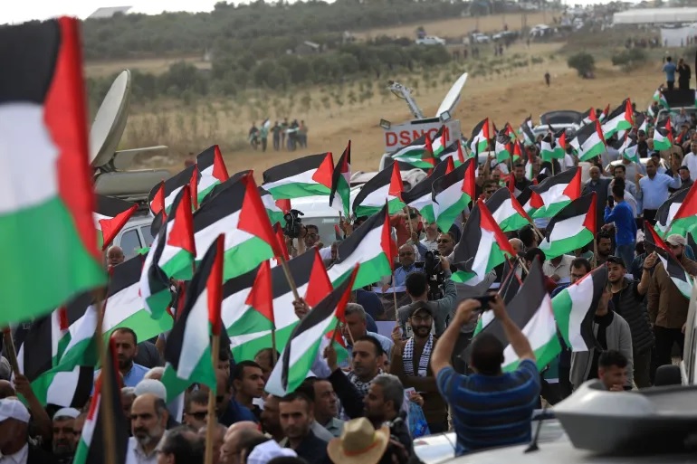 Warga Palestina di Gaza bergabung dalam pawai di dekat perbatasan timur, memprotes pawai bendera pemukim di Yerusalem pada Kamis, 18 Mei 2023. Foto: Abdelhakim Abu Riash, Al Jazeera.