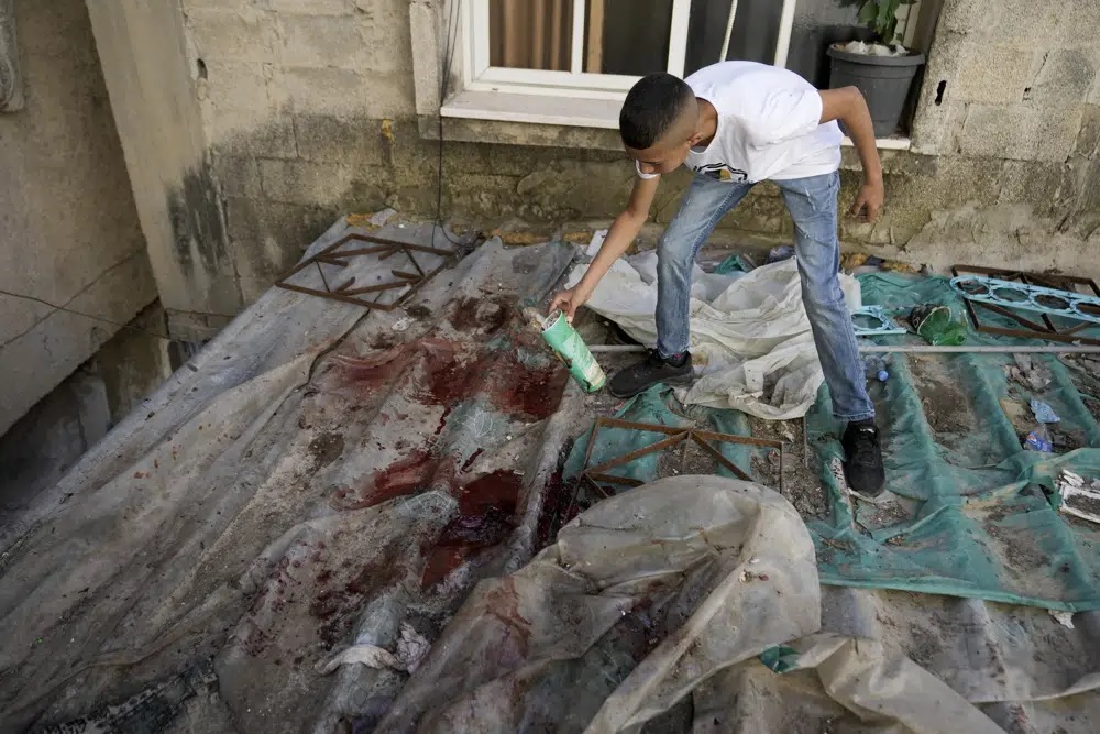 Seorang anak laki-laki melihat noda darah setelah serangan militer di kamp pengungsi Nur Shams dekat kota Tulkarem, di Tepi Barat yang diduduki Sabtu, 6 Mei 2023. Foto: Foto AP/Majdi Mohammed.