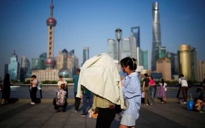 Seseorang menggunakan pakaian untuk melindungi diri dari sinar matahari, saat mereka berjalan di atas Bund pada hari yang panas, di Shanghai, China, 15 Mei 2023. Foto: Reuters/Aly Song/File Foto.