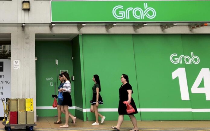 Pekerja kantor berjalan melewati kantor Grab saat jam makan siang di Singapura pada 26 Maret 2018. Foto: AP Photo/Wong Maye-E, File.