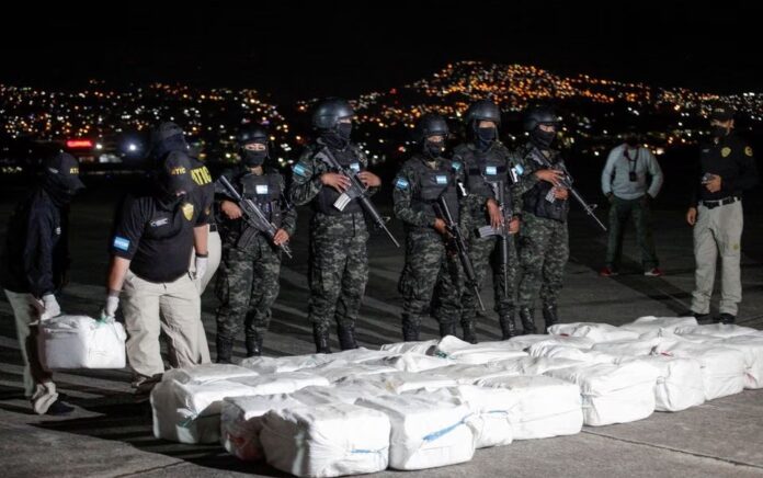 Petugas Badan Teknis Investigasi Kriminal Honduras membawa paket berisi kokain yang disita selama operasi polisi, dalam presentasi ke media, di Tegucigalpa, Honduras, 11 Desember 2022. Foto: Reuters/Fredy Rodriguez.