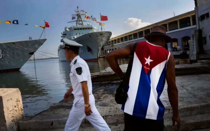 Seorang pria yang mengenakan kemeja dengan bendera Kuba melihat kapal Angkatan Laut China yang baru tiba di pelabuhan Havana, Kuba pada tahun 2015. Foto: Ramon Espinosa/The Associated Press.