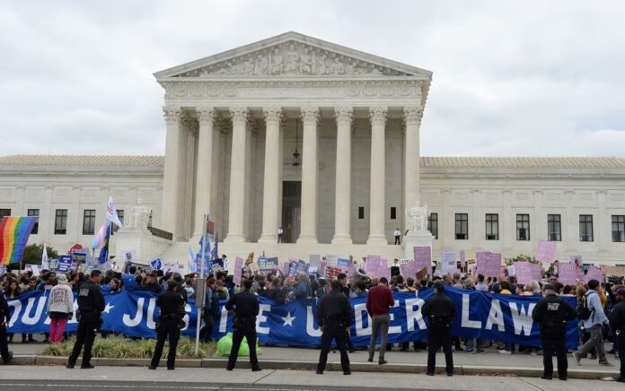 Polisi Capitol Amerika Serikat berbaris di sepanjang perimeter sementara para aktivis dan pendukung LGBTQ mengadakan rapat umum di tangga Mahkamah Agung saat mendengarkan kasus besar hak-hak LGBT tentang apakah undang-undang ketenagakerjaan federal yang melarang diskriminasi atas dasar jenis kelamin mencakup orientasi seksual dan identitas gender , di Washington, AS, 8 Oktober 2019. Foto: Reuters/Mary F. Calvert.