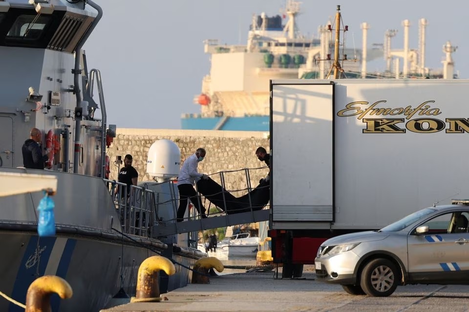 Para pria memindahkan kantong jenazah yang membawa migran yang tewas setelah kapal mereka terbalik di laut lepas Yunani, di atas kapal Penjaga Pantai Hellenic di pelabuhan Kalamata, Yunani, 15 Juni 2023. Foto: Reuter/Stelios Misinas.