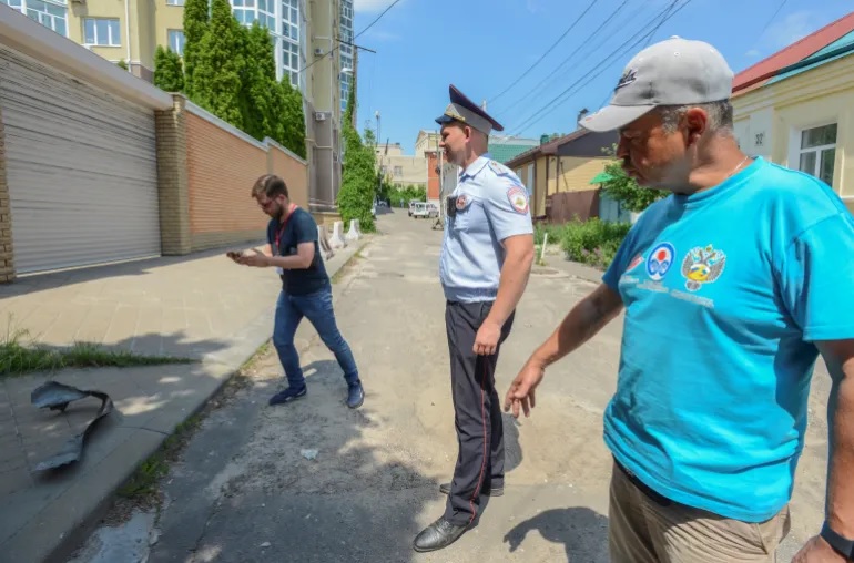Seorang petugas polisi berjaga-jaga ketika wartawan merekam di dekat blok apartemen bertingkat yang rusak menyusul laporan serangan pesawat tak berawak di Voronezh, Rusia 9 Juni 2023. Foto: Reuters/Vladimir Lavrov.