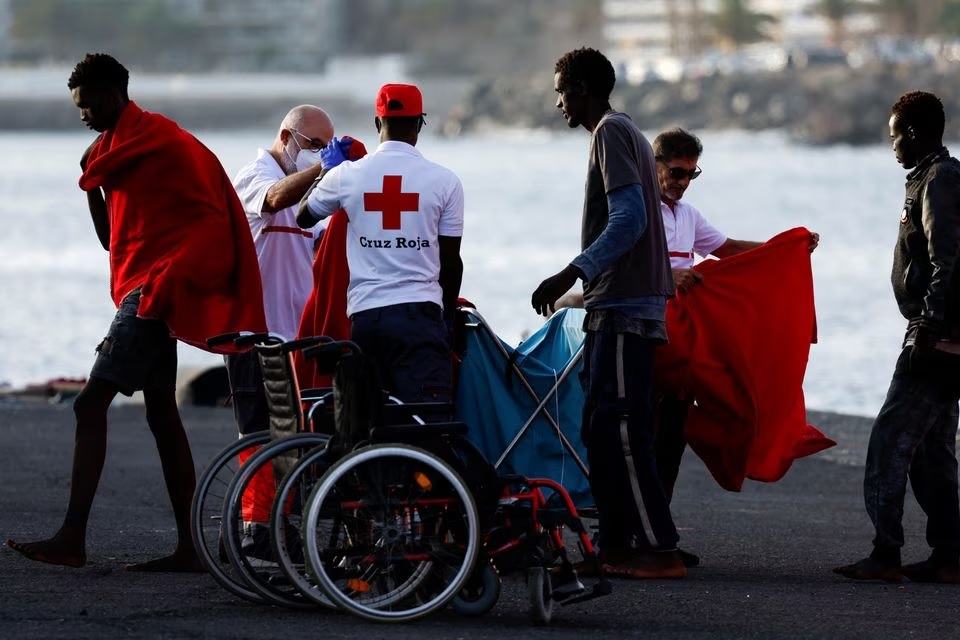 Migran berjalan menuju tenda Palang Merah setelah turun dari kapal penjaga pantai Spanyol di pelabuhan Arguineguin, pulau Gran Canaria, Spanyol, 10 Juli 2023. Foto: Reuters/Borja Suarez.