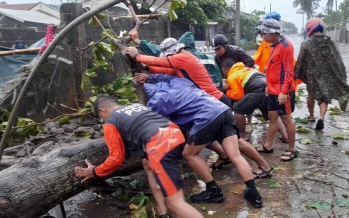 Anggota Penjaga Pantai Filipina memindahkan pohon tumbang dari jalan setelah serangan hebat Topan Doksuri di Buguey, provinsi Cagayan, Filipina, 26 Juli 2023. Foto: Penjaga Pantai Filipina/HO/Reuters.