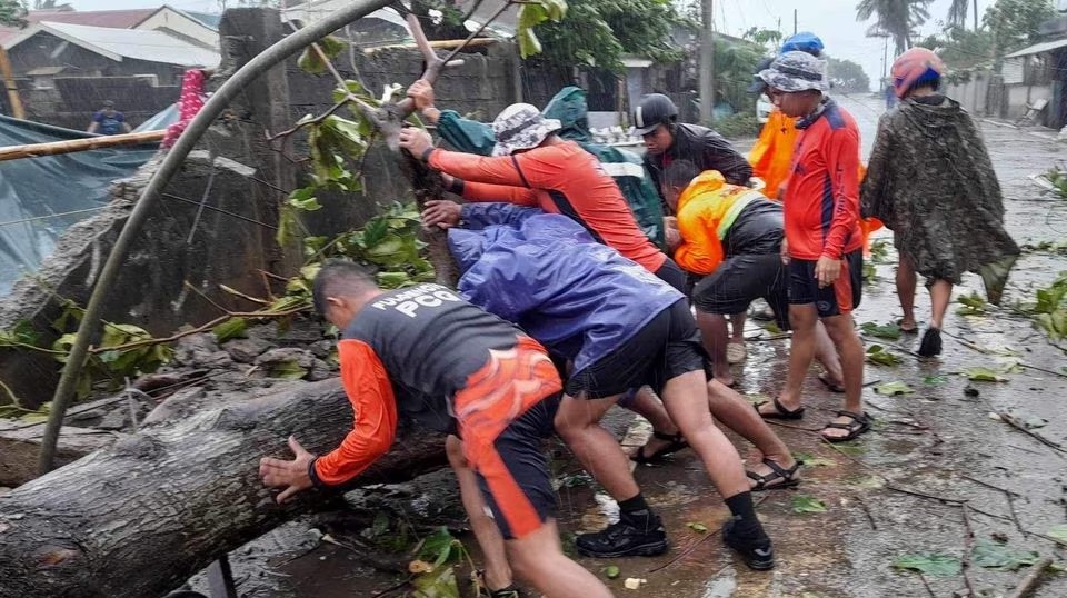 Anggota Penjaga Pantai Filipina memindahkan pohon tumbang dari jalan setelah serangan hebat Topan Doksuri di Buguey, provinsi Cagayan, Filipina, 26 Juli 2023. Foto: Penjaga Pantai Filipina/HO/Reuters.