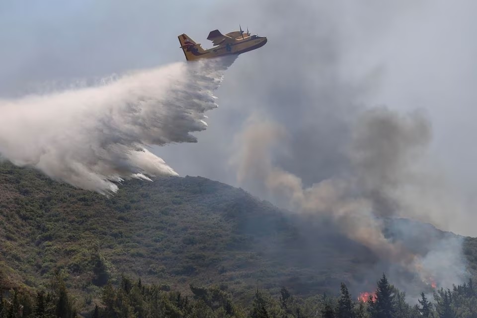 Sebuah pesawat pemadam kebakaran membuat tetesan air di pulau Rhodes, 25 Juli 2023. Foto: Reuters/Nicolas Economou.